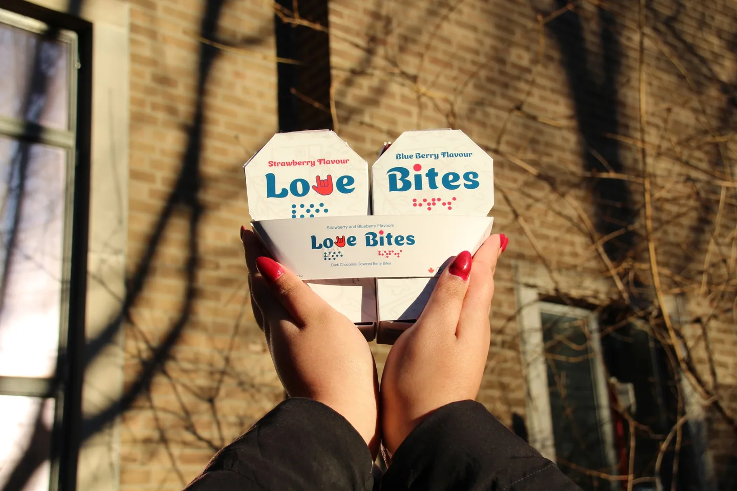 The Love Bites packs held up against a sunlit brick wall
