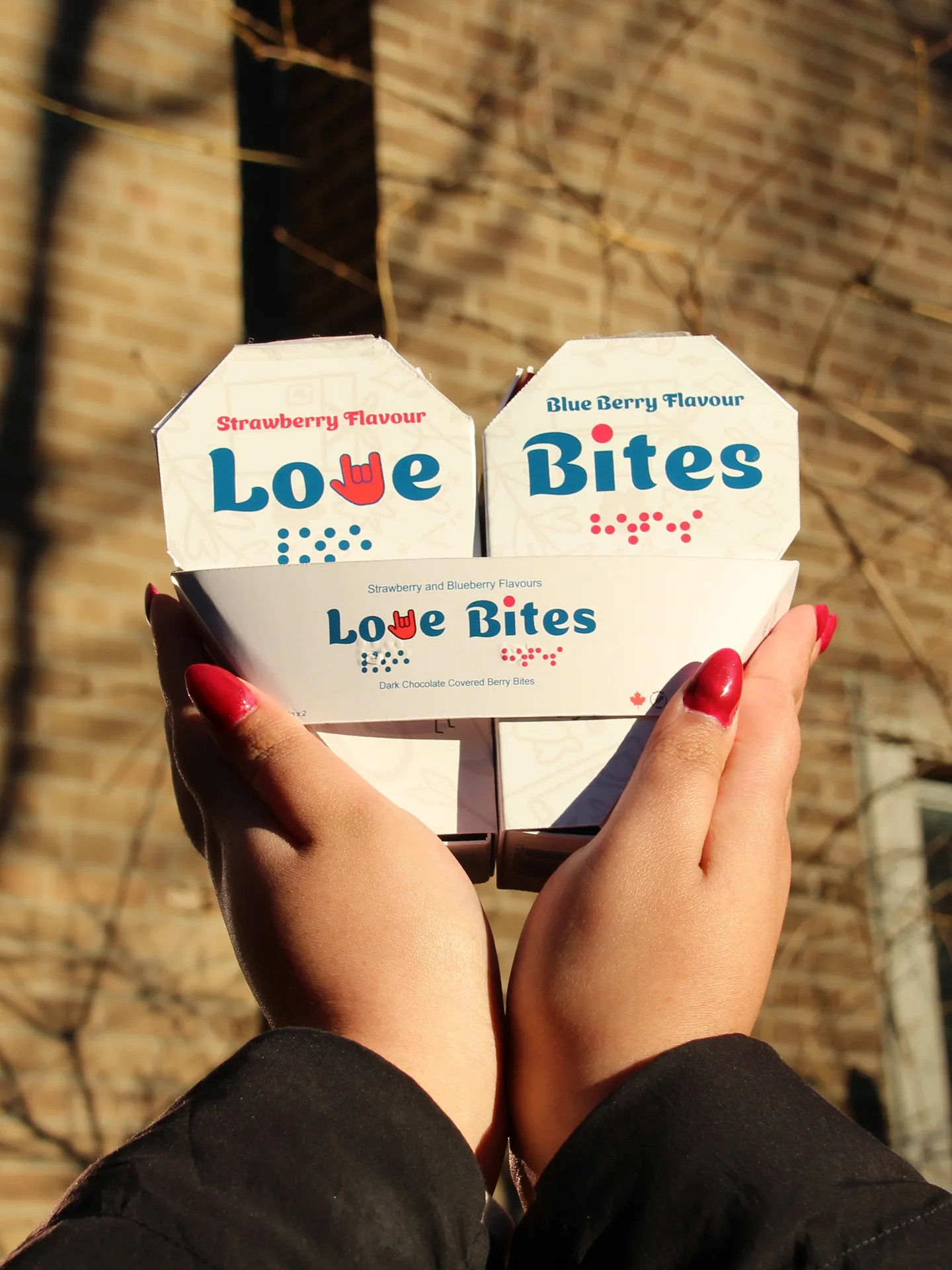 Two hands holding up the Love Bites strawberry and blueberry packs