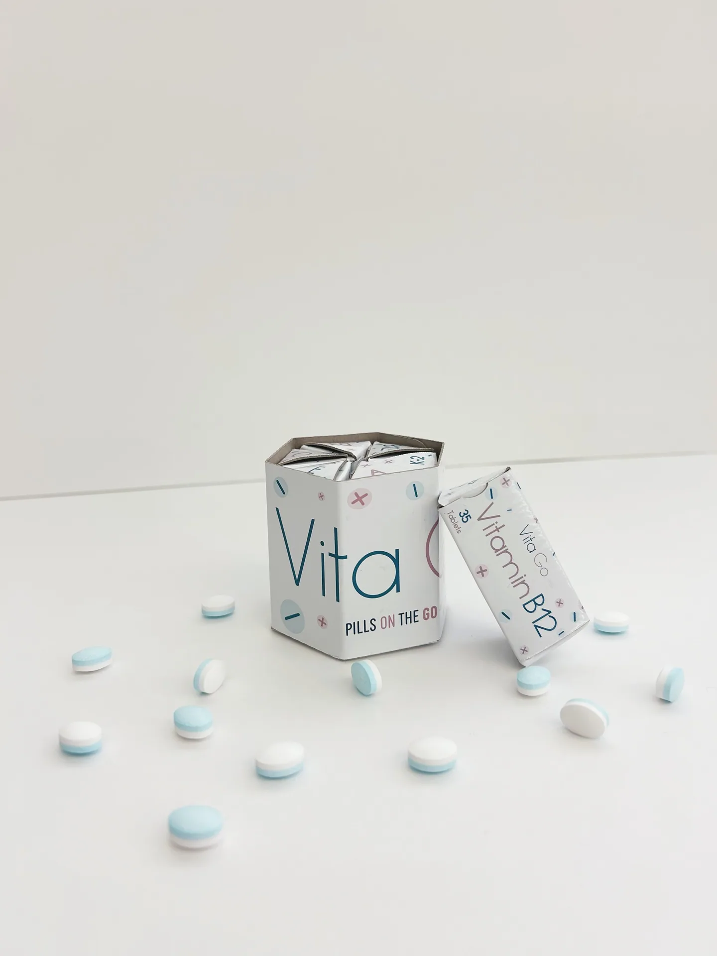 Vita Go hexagonal carton and Vitamin B12 pack with tablets scattered around them